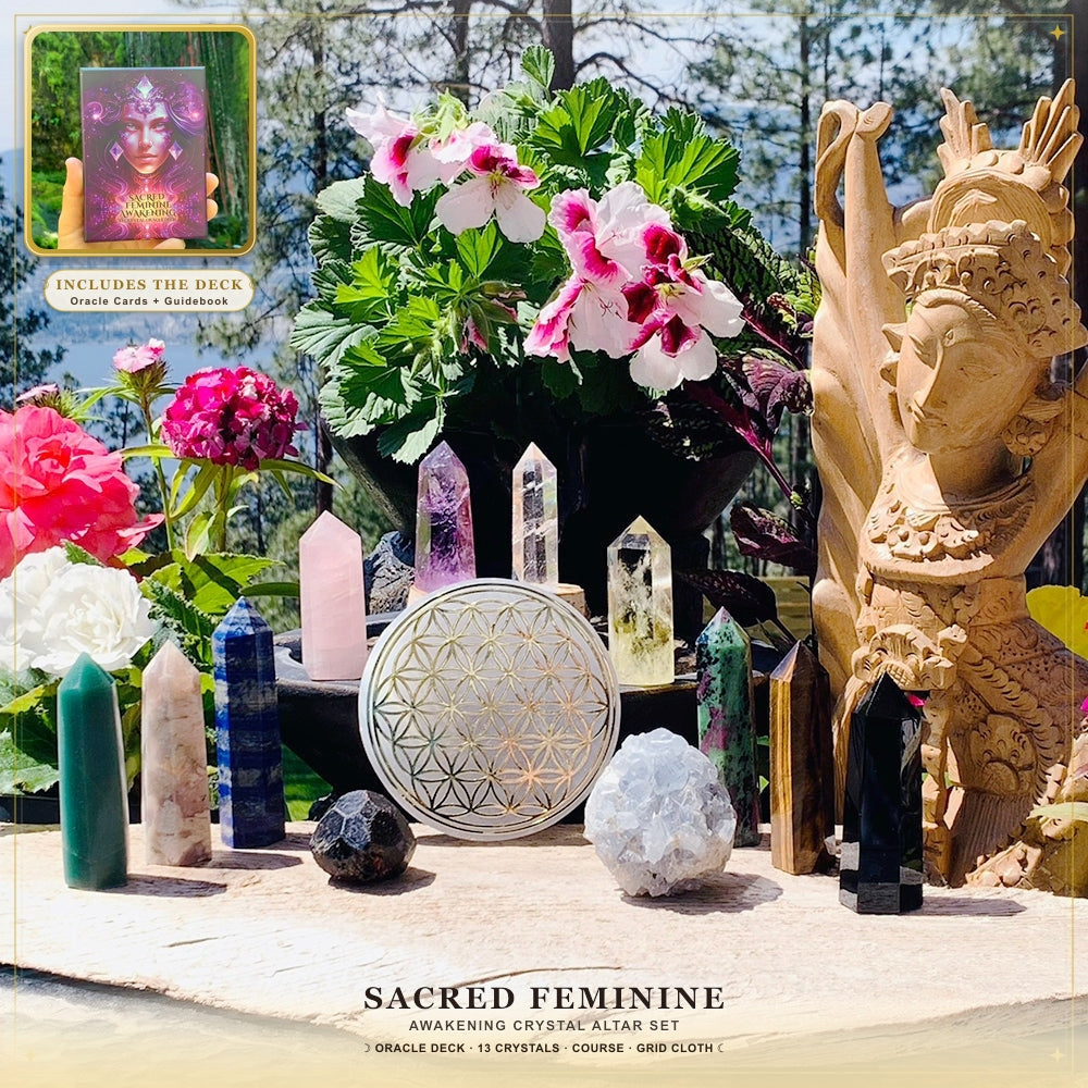 The thirteen crystals of the altar set arranged outdoors around the selenite Flower of Life disk, with flowers and a carved goddess statue behind