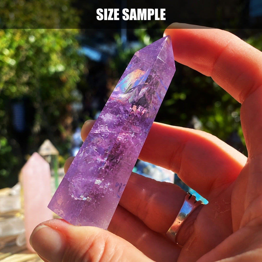 A hand holding an amethyst point to demonstrate scale