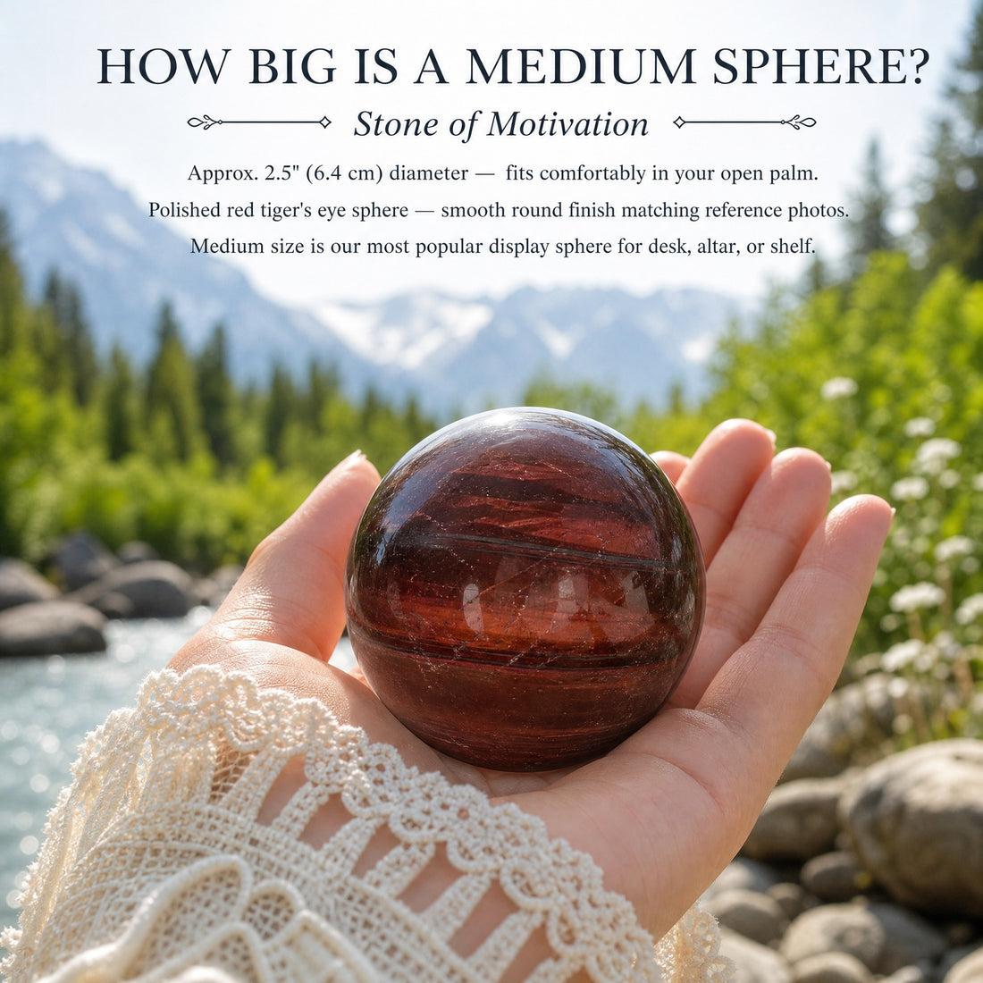 A polished red tiger’s eye sphere resting in an open palm beside a mountain river