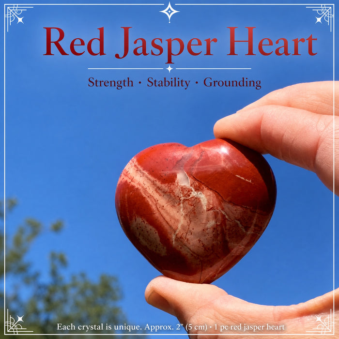 Red jasper heart with cream veining held against a blue sky