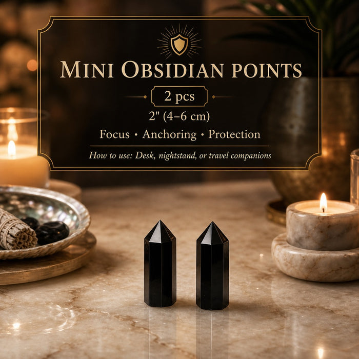 Two mini obsidian points on a marble tabletop