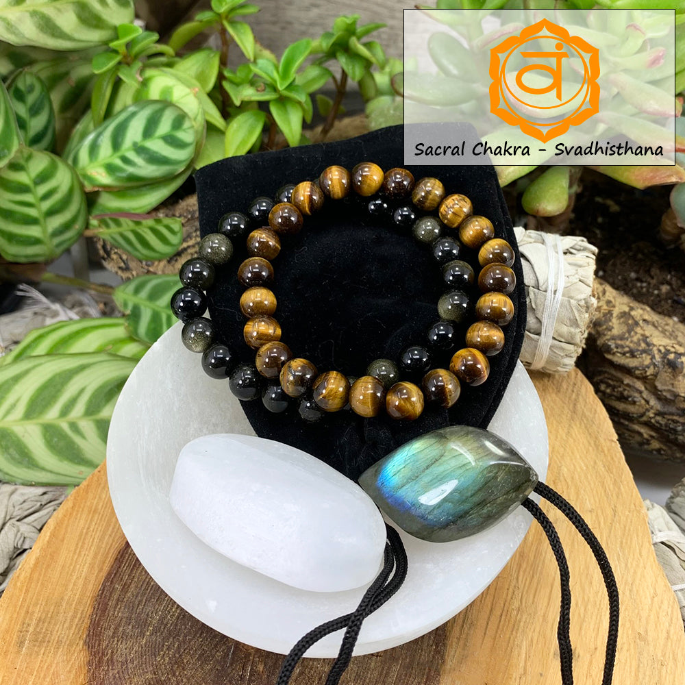 Tiger's eye and golden obsidian mala bracelets on a black velvet pouch with a white selenite ellipse and a blue-flashing labradorite cabochon