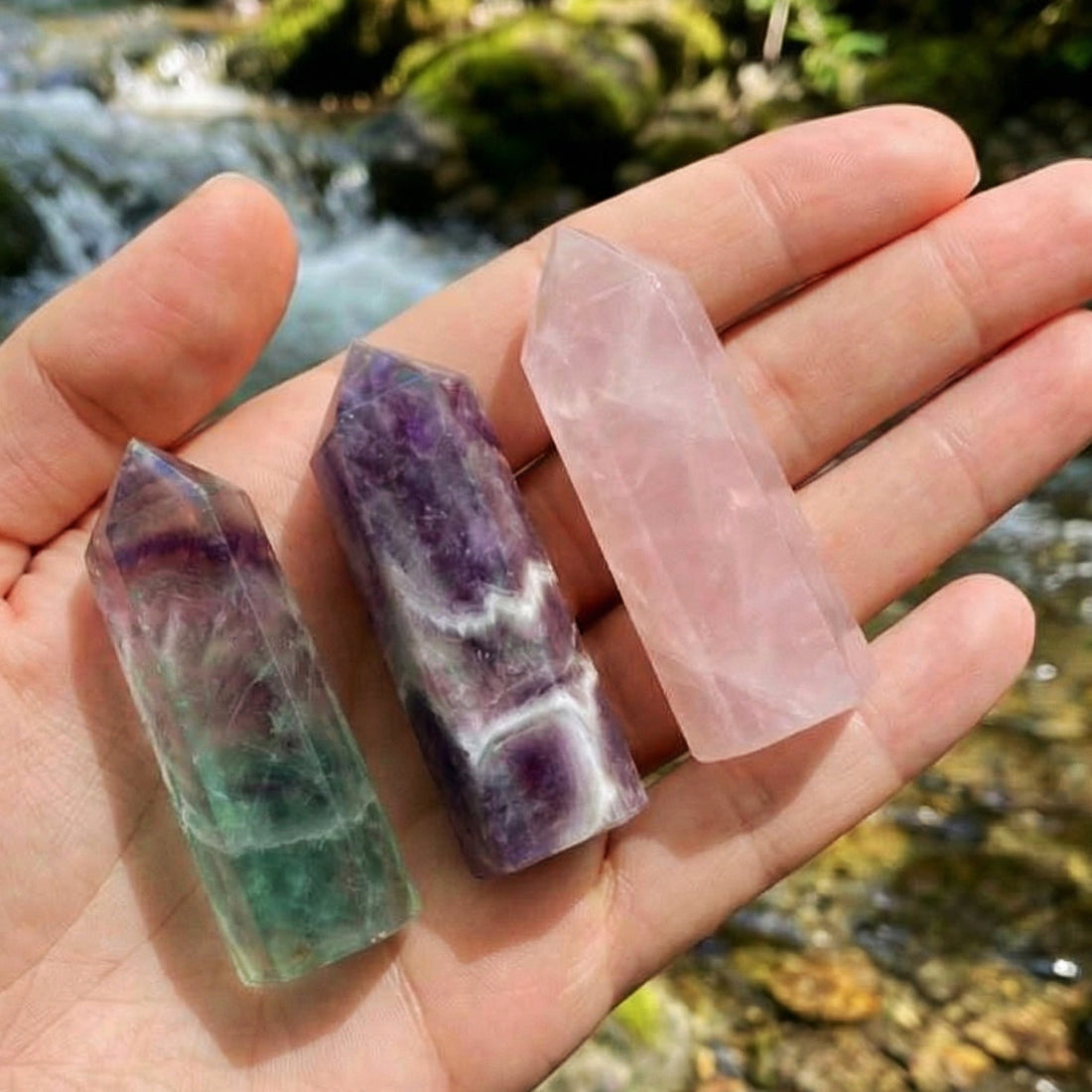 The fluorite, dream amethyst and rose quartz mini points lying across an open palm