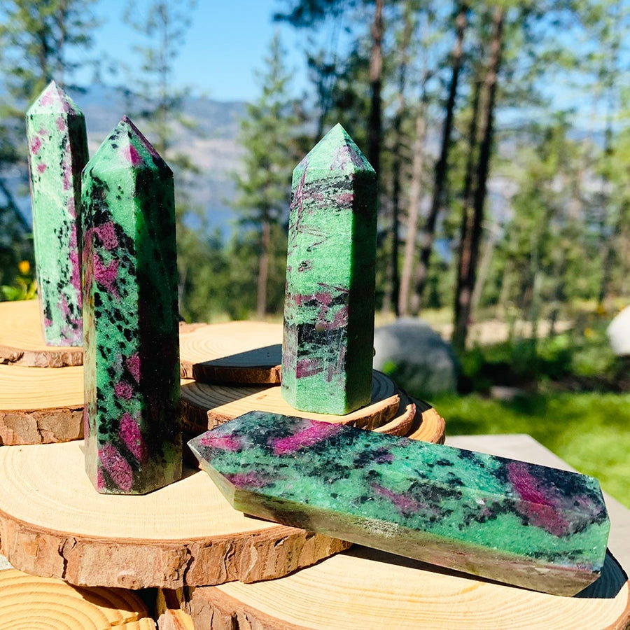 Four ruby in zoisite points on wooden rounds, each with its own mix of green, black and pink