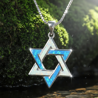 Close-up of the interlaced sterling silver Star of David pendant inlaid with blue and white opal, on a box chain against moss