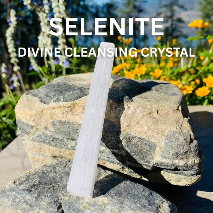 A white selenite stick standing on a grey rock