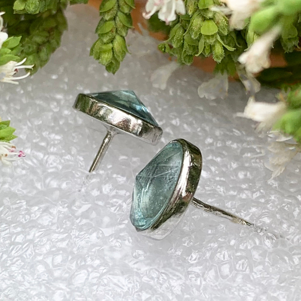 Side view of the two aquamarine studs showing their faceted stones, silver bezels and posts