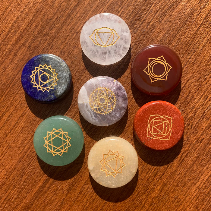 Seven round chakra stones engraved with gold chakra symbols