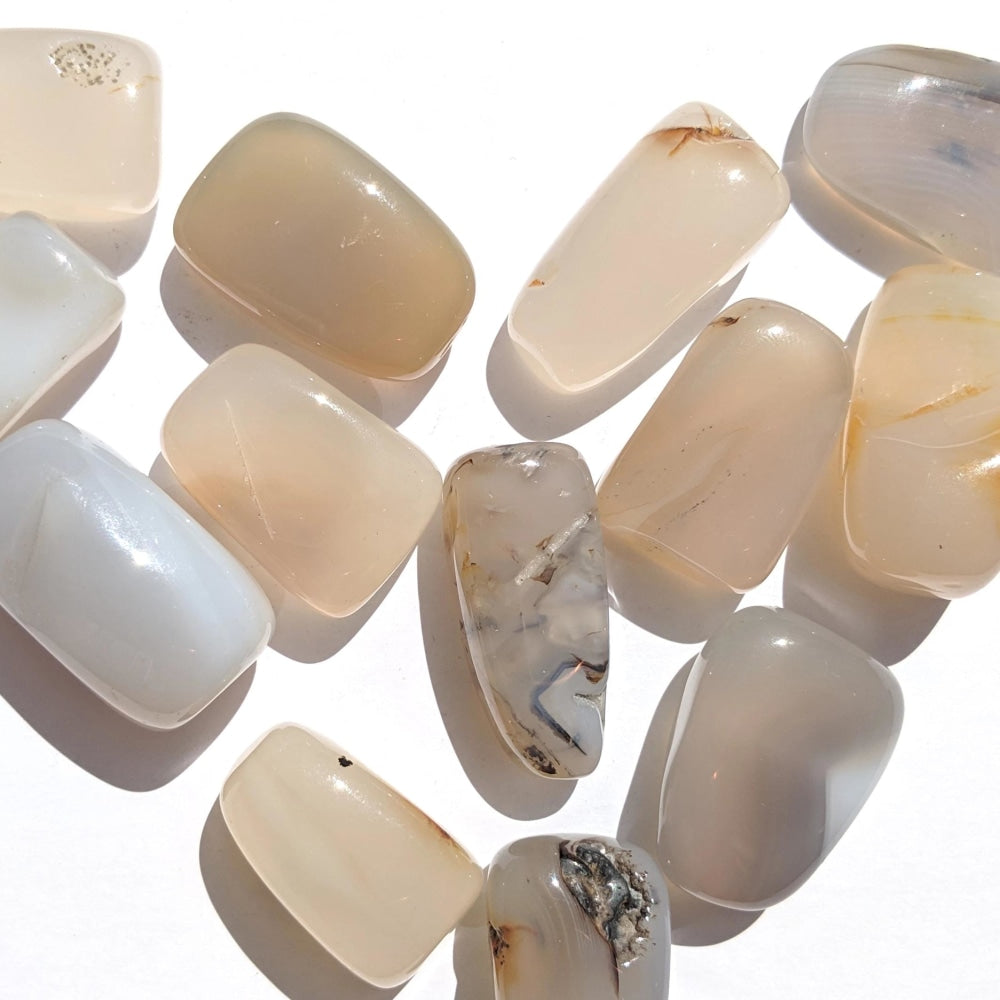 Polished chalcedony tumbled stones in translucent milky white, cream and soft grey, some with darker inclusions