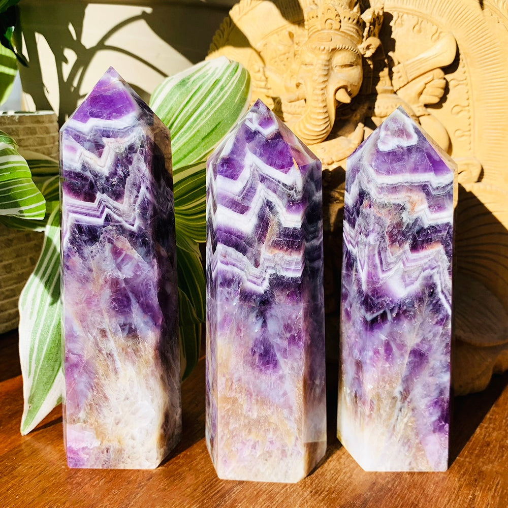 Three dream amethyst generators side by side in sunlight, each with a different pattern of purple and white chevrons
