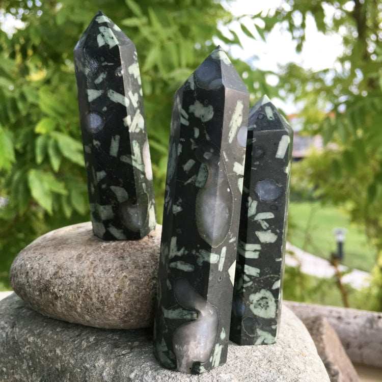 Three flower quartz agate points standing on garden stones, each with its own scatter of pale patterns