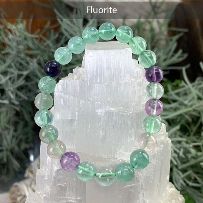 Green and purple fluorite bead bracelet on a selenite tower