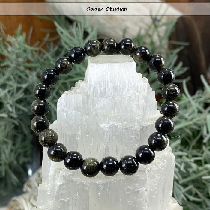 Glossy black golden obsidian bead bracelet on a selenite tower