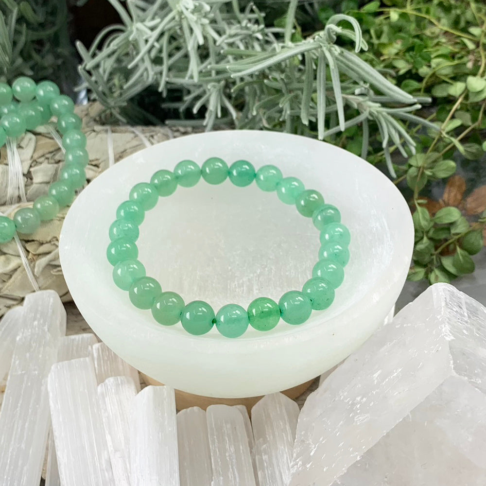 Green aventurine mala bracelet of round 8 mm beads resting in a selenite bowl