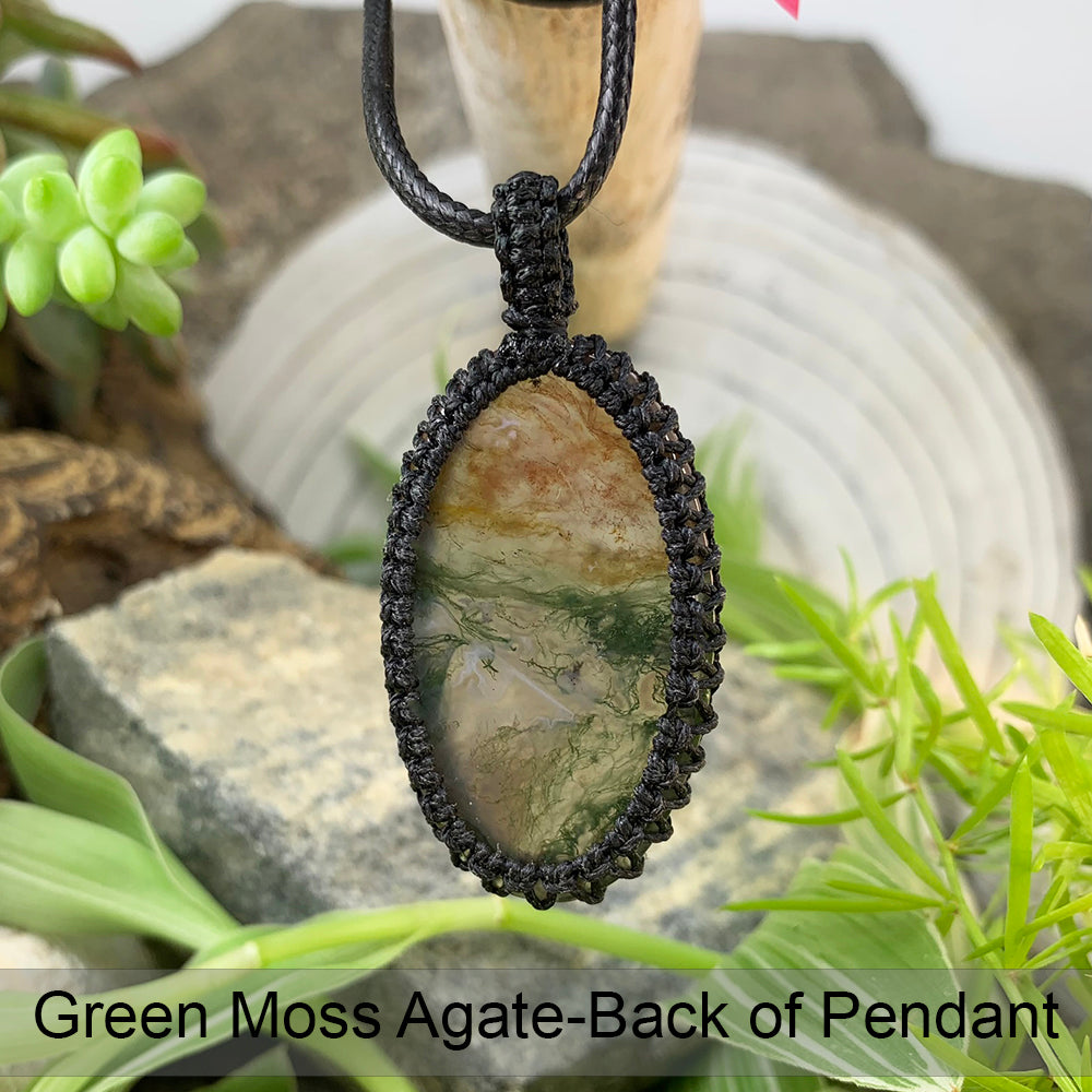 The back of the moss agate pendant in its black macramé setting, hanging from a black cord
