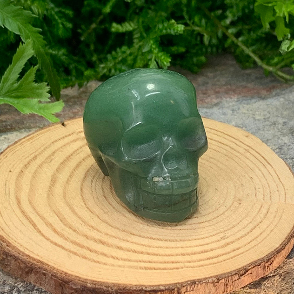 Soft green chalcedony quartz skull totem facing forward on a wooden slice