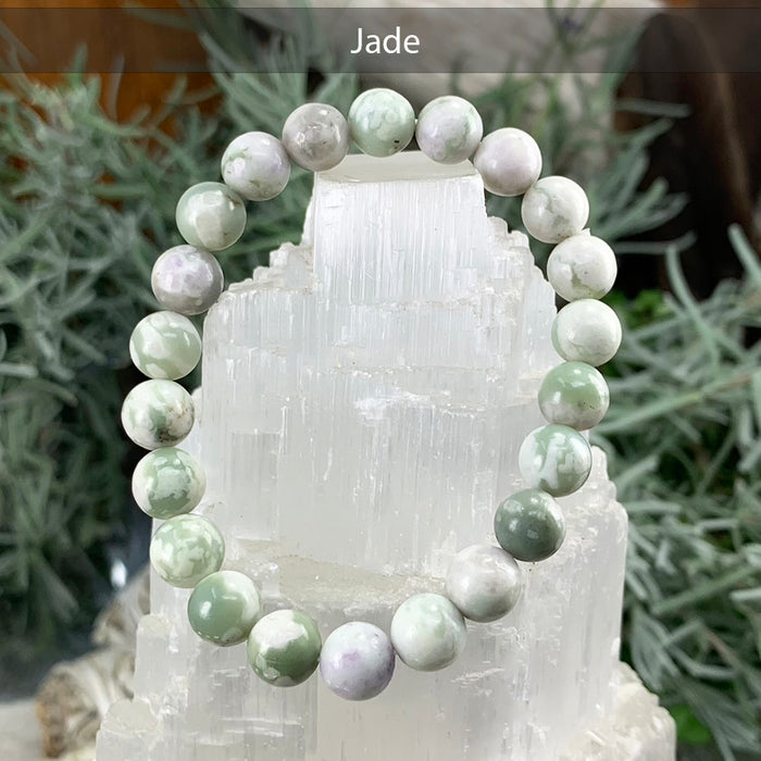 Green and white jade bead bracelet on a selenite tower