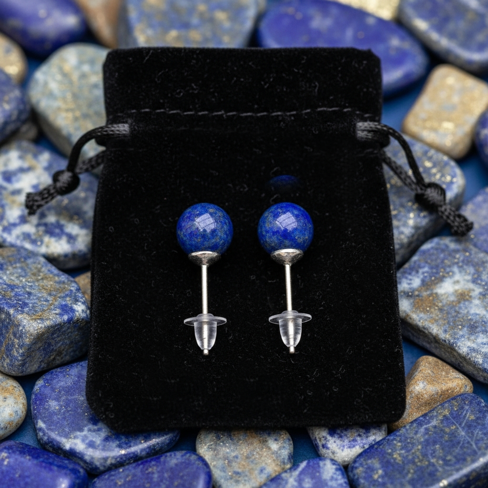 The two lapis lazuli studs on their posts with clear earring backs, laid on a black velvet drawstring pouch