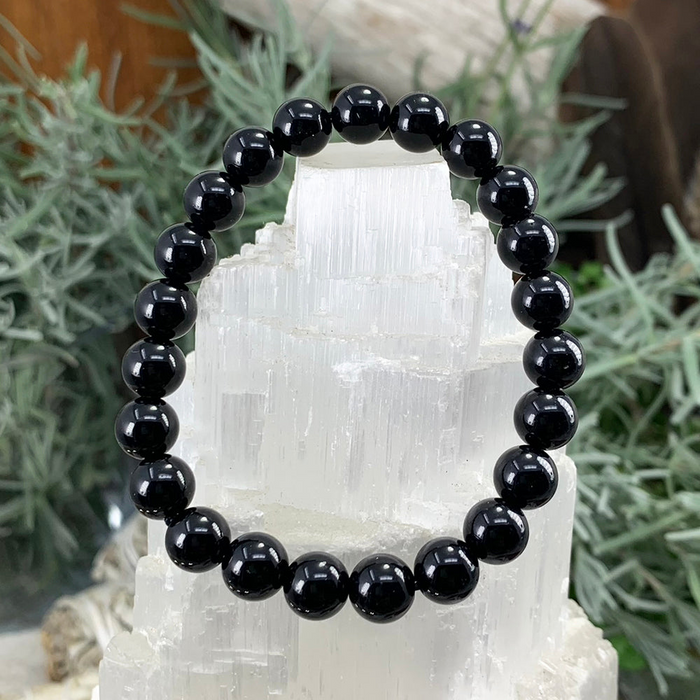 A black obsidian bead bracelet on a white selenite cluster