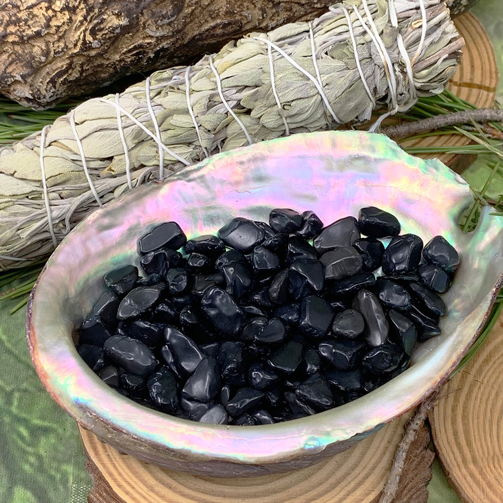 Black obsidian mini gemstones displayed in an iridescent abalone shell beside sage bundles