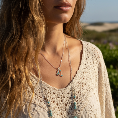 The Leo opal pendant worn on its fine silver chain over a cream crochet top, by the sea