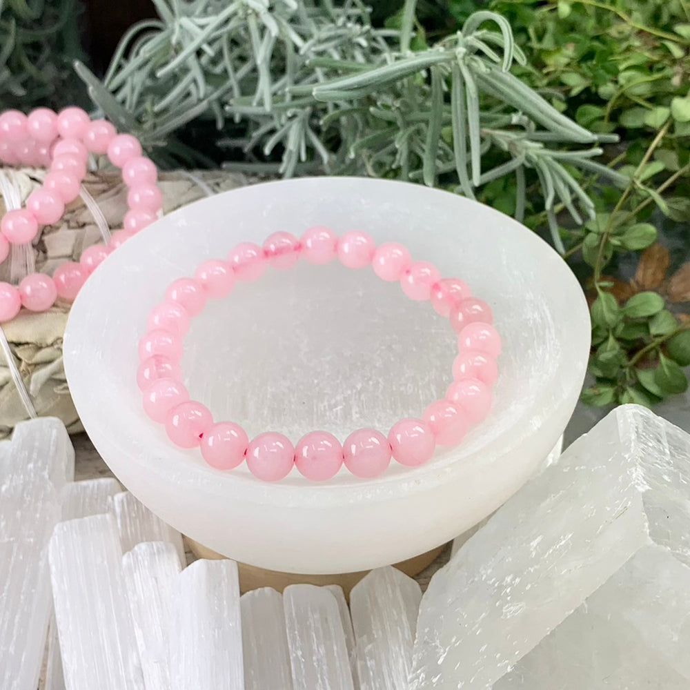 Pale pink rose quartz bead bracelet resting in a white selenite bowl