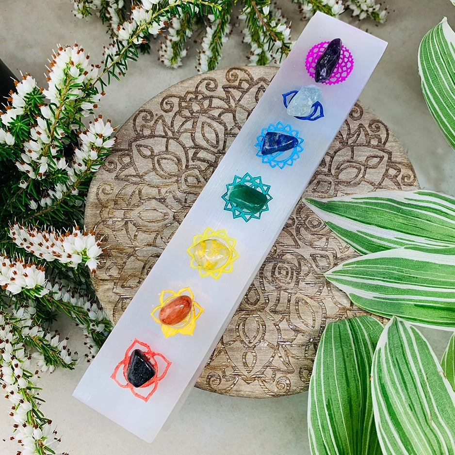 Selenite charging plate engraved with seven colored chakra symbols, a matching mini gemstone resting on each symbol