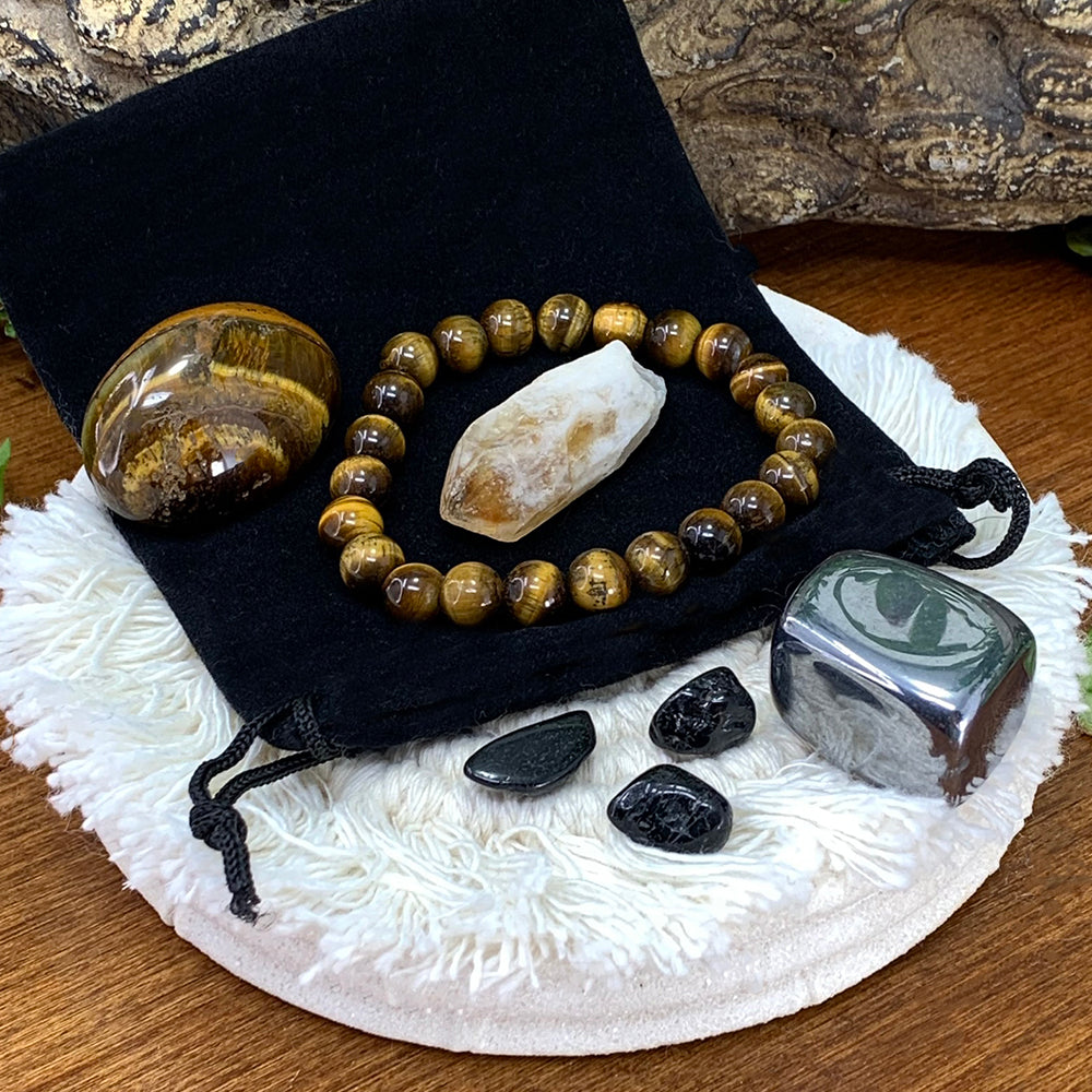 Tiger's eye bead bracelet on a black velvet pouch with a tiger's eye tumble, a citrine shard, a hematite cube and three small black tourmaline stones