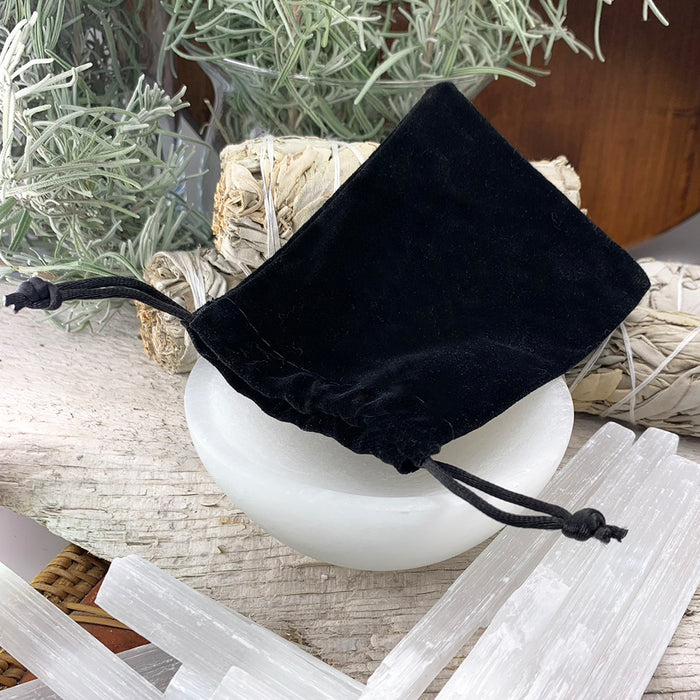 Black velvet drawstring pouch resting on a selenite bowl