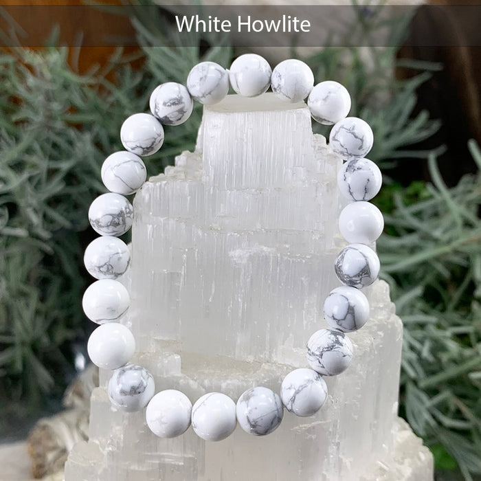 White Howlite bracelet with snowy white beads and fine grey veining, displayed on a selenite tower